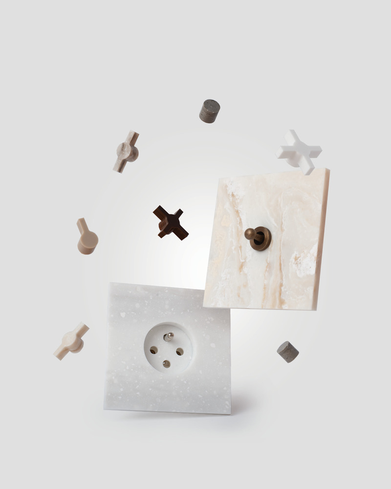 Dossier de presse | 7628-01 - Communiqué de presse | Frame Award 2024 winning switches & sockets - Bright Little Things - Produit - Basic finishing  component 5101 in Corian June Prima with aged brass Little Twist switch - finishing component 5102 (socket) in Alabaster Kerrock - buttons Berlin, Paris, London, and Amsterdam from the collection New Things  - Crédit photo : Lyanne Smulders