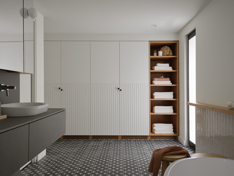 Press kit | 7600-02 - Press release | Shield and Shelter: An Embracing Lakeside Family Retreat that Opens Intimately and Sensitively to its Untamed Surroundings in the Heart of the Muskoka Region - Barbora Vokac Taylor Architect Inc. (BVT A) - Residential Architecture -  View of the master ensuite: Hand-painted cement tiles create a rich textural pattern across the heated floor. A contemporary interpretation of traditional cottage beadboard adorns the lower half of the closet doors, while offset door handles offer both whimsy and practicality, preventing pinched fingers.  - Photo credit: Doublespace