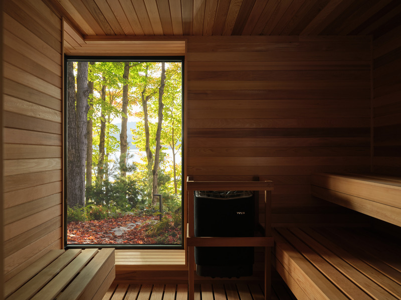 Press kit | 7600-02 - Press release | Shield and Shelter: An Embracing Lakeside Family Retreat that Opens Intimately and Sensitively to its Untamed Surroundings in the Heart of the Muskoka Region - Barbora Vokac Taylor Architect Inc. (BVT A) - Residential Architecture -  View from the Sauna towards the lake: The cottage stands in contrast to its natural setting. Carefully framed views of the landscape connect the modern spaces to their surroundings.  - Photo credit: Doublespace