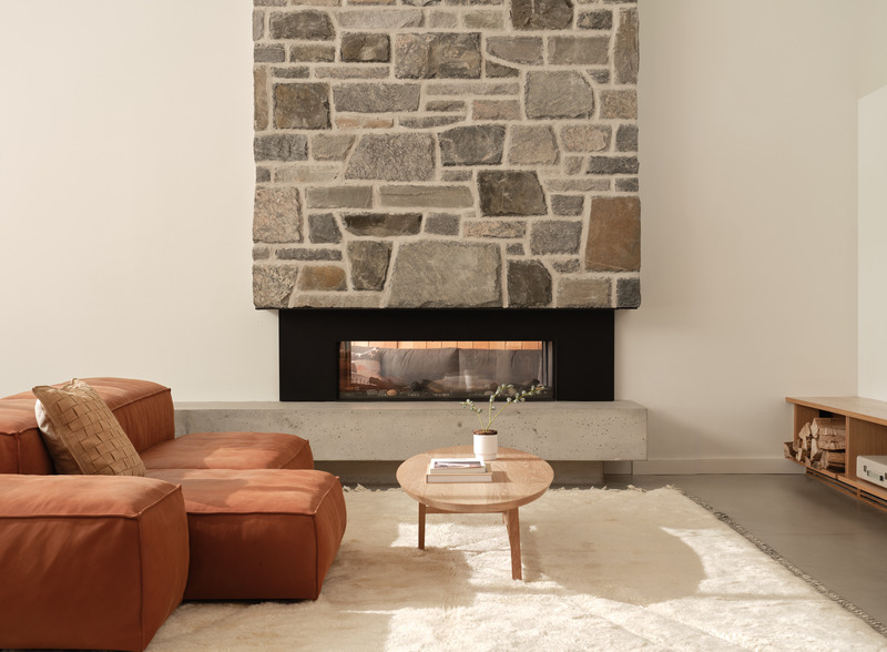Press kit | 7600-02 - Press release | Shield and Shelter: An Embracing Lakeside Family Retreat that Opens Intimately and Sensitively to its Untamed Surroundings in the Heart of the Muskoka Region - Barbora Vokac Taylor Architect Inc. (BVT A) - Residential Architecture -  The living room features a double-sided fireplace, with a grand stone chimney adding aesthetic beauty as it rises through the levels of the structure to the exterior.  - Photo credit: Doublespace