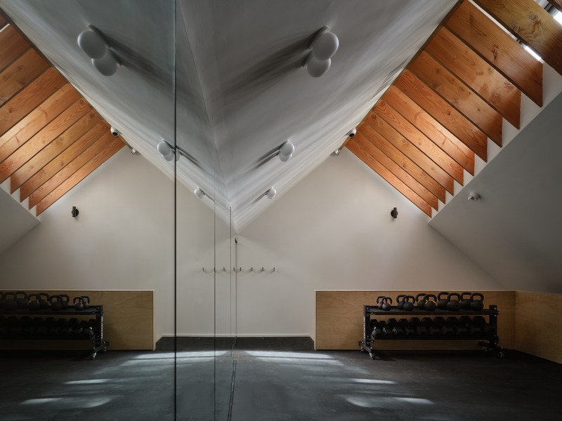 Press kit | 7600-02 - Press release | Shield and Shelter: An Embracing Lakeside Family Retreat that Opens Intimately and Sensitively to its Untamed Surroundings in the Heart of the Muskoka Region - Barbora Vokac Taylor Architect Inc. (BVT A) - Residential Architecture -   Mirrors line one wall of the fitness room above the garage, capturing natural light from the opposite clerestory windows and highlighting the exposed Douglas fir joists. The wandering shadows bring the space to life - each hour offering a new and unique atmosphere.   - Photo credit: Doublespace