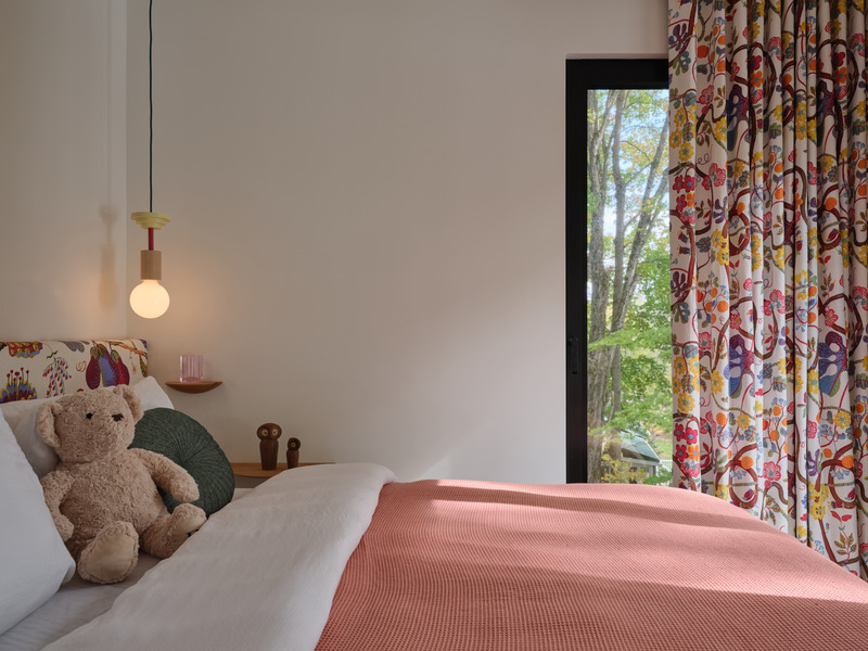 Press kit | 7600-02 - Press release | Shield and Shelter: An Embracing Lakeside Family Retreat that Opens Intimately and Sensitively to its Untamed Surroundings in the Heart of the Muskoka Region - Barbora Vokac Taylor Architect Inc. (BVT A) - Residential Architecture -  Bold Josef Frank florals enliven the drapery and upholstery. The artful mix of patterns adds depth and character to the bedroom.  - Photo credit: Doublespace