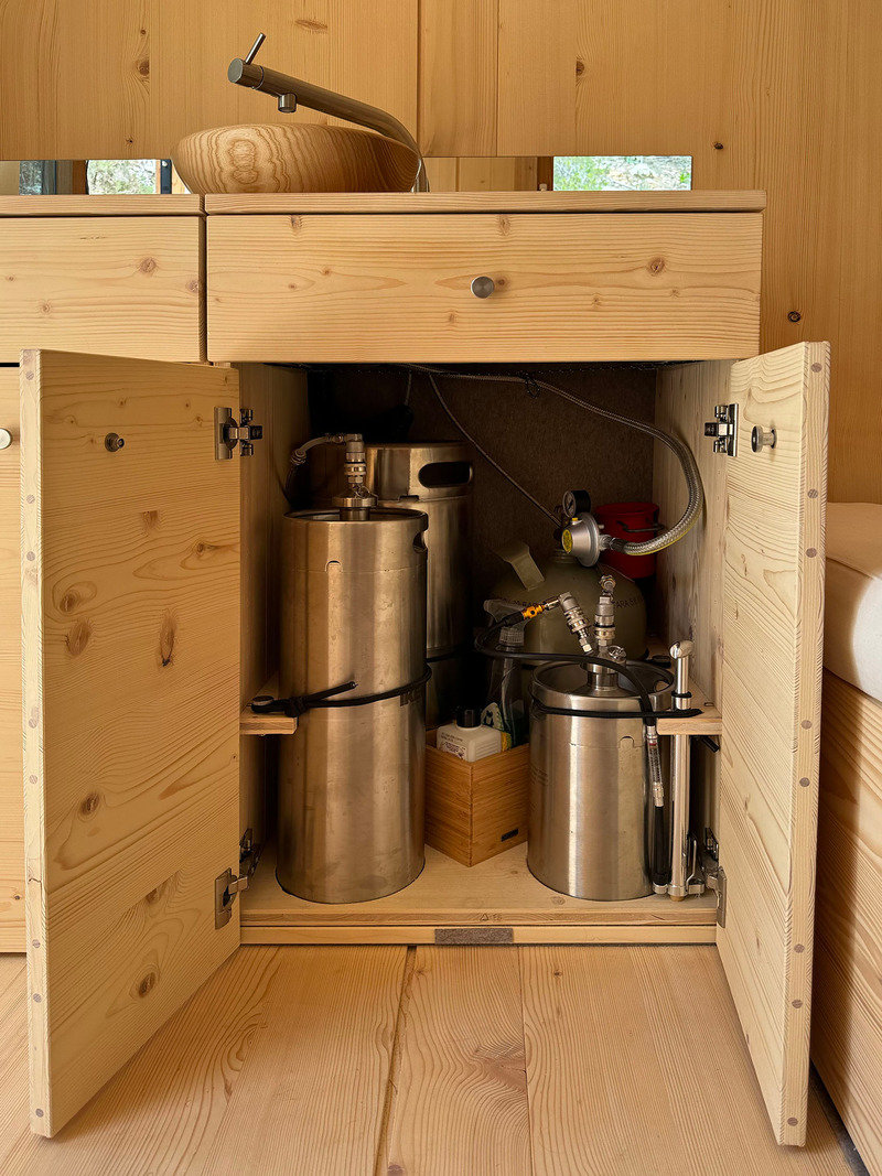 Press kit | 7649-02 - Press release | COCOON Freelancer -  Free of Glue, Chemicals and Plastic - AttiaDesign & Weidlich moon-wood manufactory - Lifestyle -  Equipped with 5Kg gas cooktop, and 18L running water, stainless steel tanks,  - Photo credit: AttiaDesign