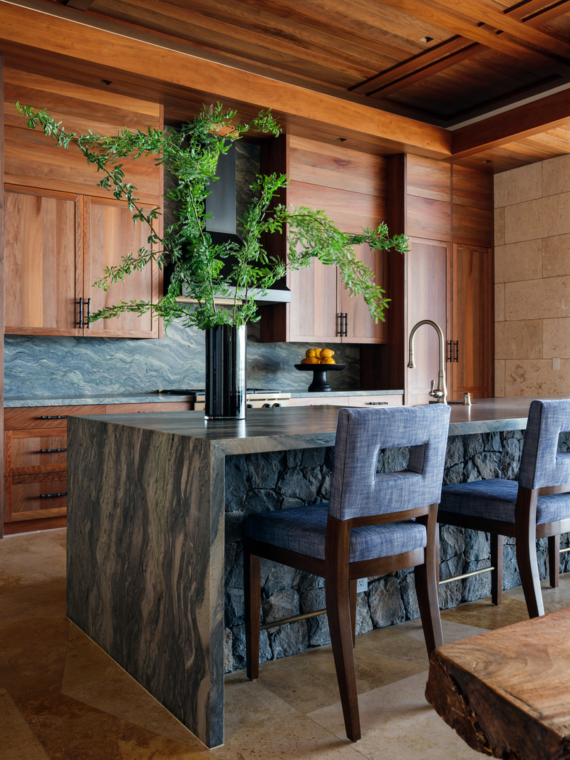 Dossier de presse | 2757-48 - Communiqué de presse | Three Hawaiian Residences By Philpotts Interiors Elevate Island Living - Philpotts Interiors - Design d’intérieur résidentiel - Coral House: In the kitchen, the fusion blue granite island and other surfaces quietly convey an ocean-inspired color story. The contrastingly cool elements complement extensive millwork that includes locally and sustainably sourced ohia wood cabinetry. Stools are by A. Rudin. - Crédit photo : Travis Rowan