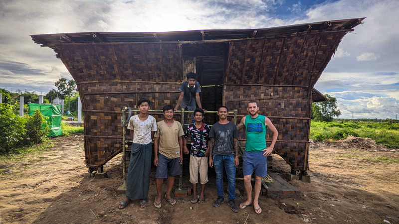 Press kit | 7035-02 - Press release | Bamboo Housing Resists 7.7 Earthquake in Conflict-Torn Myanmar, Built for Displaced Families - Blue Temple - Institutional Architecture - Construction team standing in front of a completed bamboo relief house in central Myanmar. - Photo credit: Raphaël Ascoli