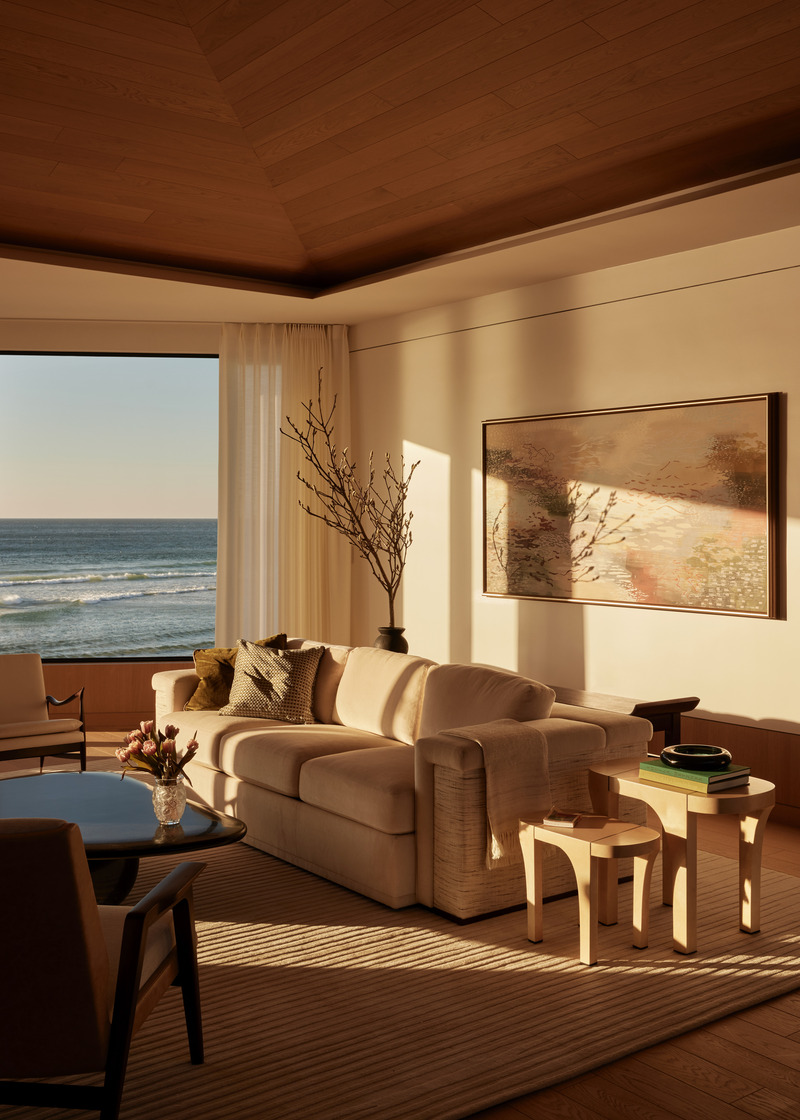 Press kit | 6087-07 - Press release | Study in Serenity: A Beachside Haven of Precision and Craftsmanship - Daniel Joseph Chenin - Residential Interior Design - Framed by a pitched oak-paneled ceiling, the living room becomes a space of reflection and calm, where curated furnishings and natural textures foster a sense of quiet restraint. Afternoon sun washes across walls and surfaces, animating the room with shifting patterns of light and shadow, while the ocean beyond transforms into living art, ever-changing throughout the day. - Photo credit: Tim Hirschmann