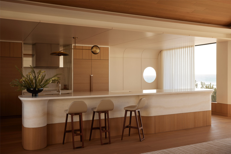 Press kit | 6087-07 - Press release | Study in Serenity: A Beachside Haven of Precision and Craftsmanship - Daniel Joseph Chenin - Residential Interior Design - The sculptural onyx island anchors the kitchen with a sense of rhythm and flow, its carved form echoing the ocean beyond while refined millwork and nautical detailing reinforce balance and precision. - Photo credit: Tim Hirschmann