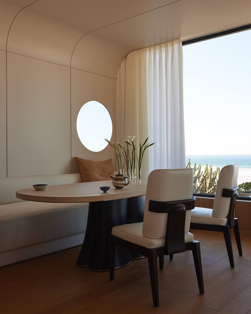 Press kit | 6087-07 - Press release | Study in Serenity: A Beachside Haven of Precision and Craftsmanship - Daniel Joseph Chenin - Residential Interior Design - The dining alcove recalls the intimacy of a yacht’s cabin, with a built-in banquette, circular port window, and panoramic glazing that frame the horizon like an ever-shifting seascape. - Photo credit: Tim Hirschmann