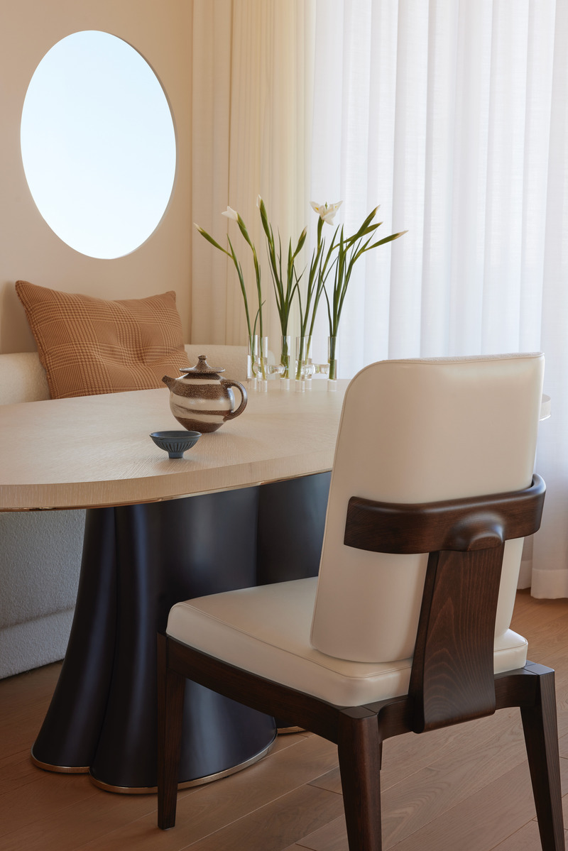 Press kit | 6087-07 - Press release | Study in Serenity: A Beachside Haven of Precision and Craftsmanship - Daniel Joseph Chenin - Residential Interior Design - Subtle craftsmanship defines the dining alcove, where a custom table with a sculptural base is set against the circular port window, framing the horizon like a nautical vignette. - Photo credit: Tim Hirschmann