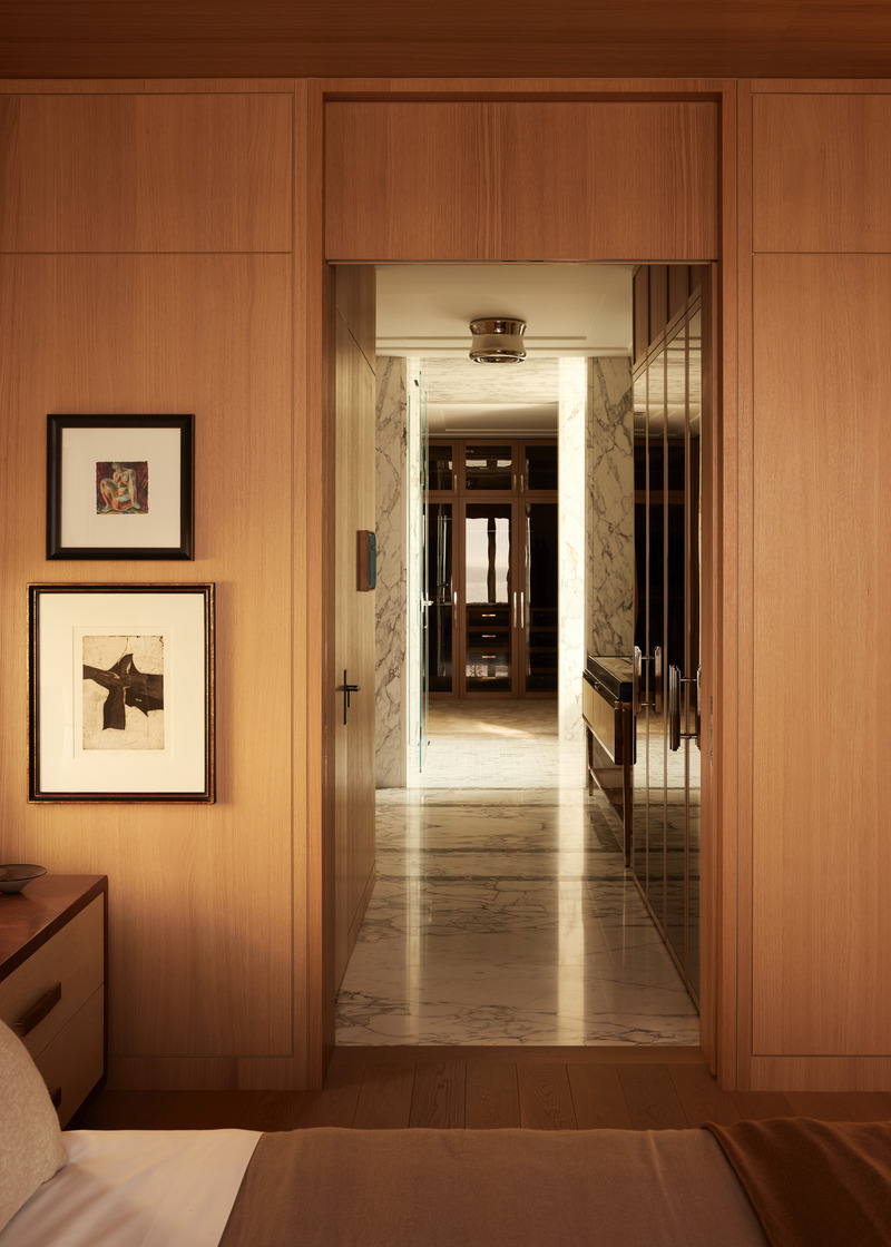 Press kit | 6087-07 - Press release | Study in Serenity: A Beachside Haven of Precision and Craftsmanship - Daniel Joseph Chenin - Residential Interior Design - From the warmth of oak-paneled walls, the bedroom opens to a marble-lined passage that leads toward the bath and dressing area, a transition that heightens the home’s choreography of texture, material, and light. - Photo credit: Tim Hirschmann