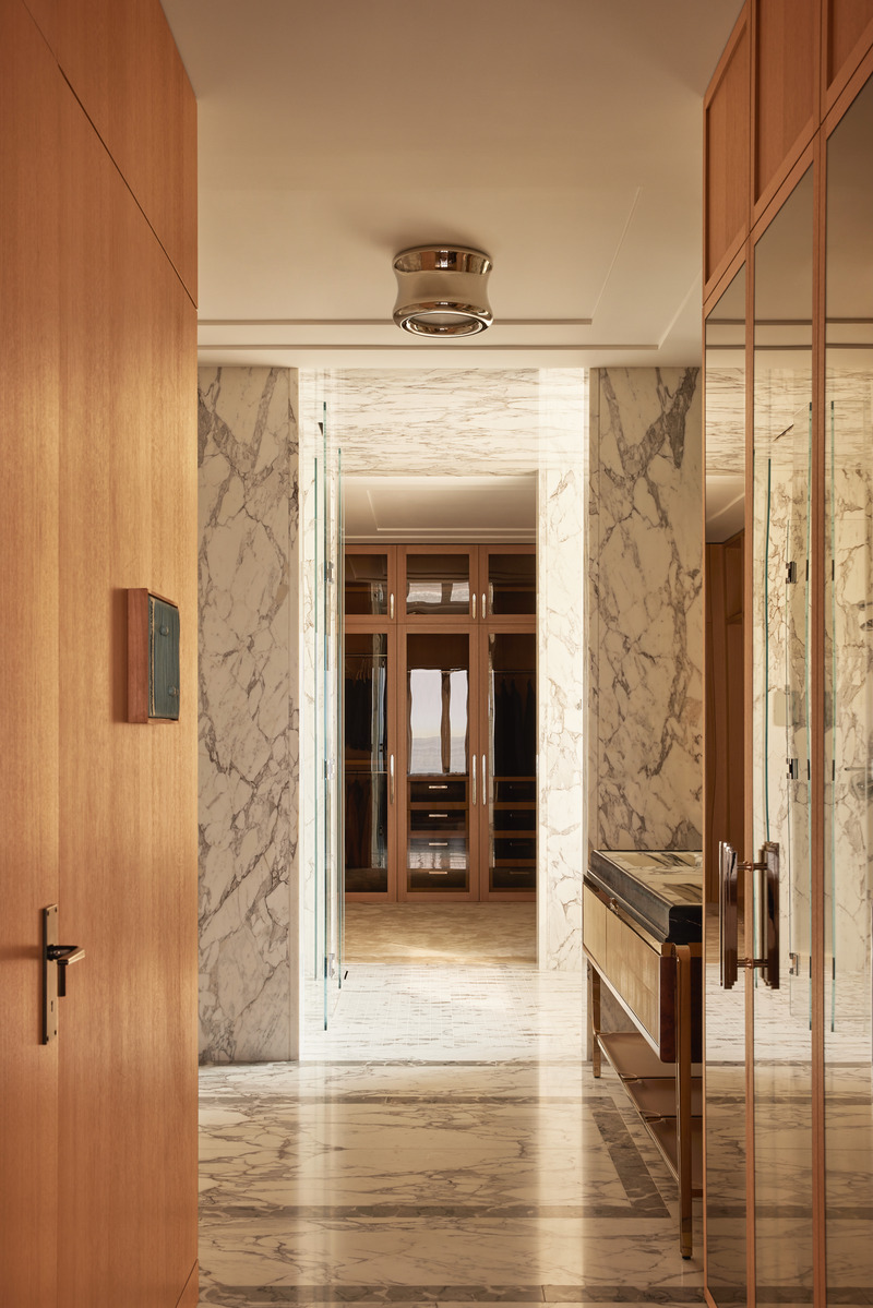 Press kit | 6087-07 - Press release | Study in Serenity: A Beachside Haven of Precision and Craftsmanship - Daniel Joseph Chenin - Residential Interior Design - Veined marble wraps the bath and corridor, leading into a finely crafted dressing room where oak millwork and mirrored panels heighten the sense of depth, reflection, and rhythm. - Photo credit: Tim Hirschmann
