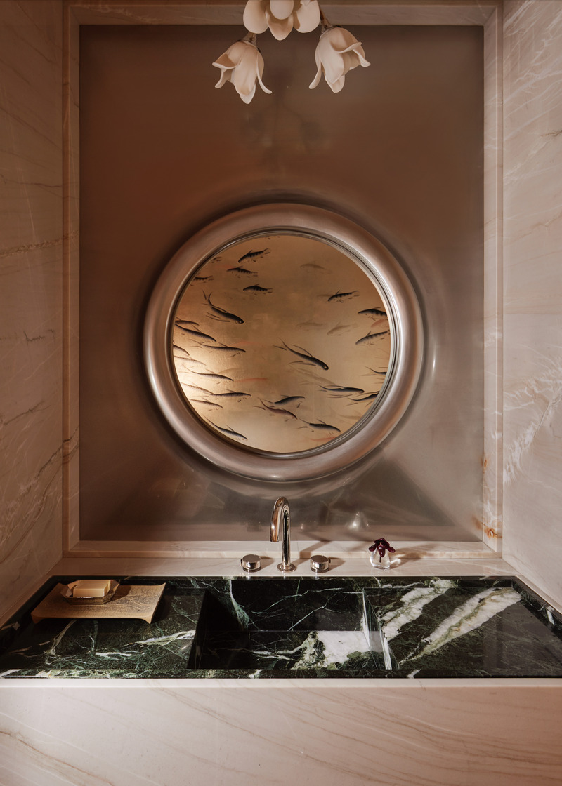 Press kit | 6087-07 - Press release | Study in Serenity: A Beachside Haven of Precision and Craftsmanship - Daniel Joseph Chenin - Residential Interior Design - In the powder room, the sea becomes a narrative, a circular port-like mirror framed in silver reflects the poetry of life beneath the surface, where hand-painted fish drift alongside floral motifs. Anchored by a dark green marble vanity, the space unfolds as a story of water, nature, and quiet reflection. - Photo credit: Tim Hirschmann