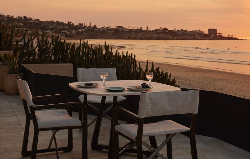 Press kit | 6087-07 - Press release | Study in Serenity: A Beachside Haven of Precision and Craftsmanship - Daniel Joseph Chenin - Residential Interior Design - An intimate dining terrace hovers above the shoreline, where cactus silhouettes meet the Pacific horizon. As the sun sets, the table becomes a stage for quiet conversation, elevated by the rhythm of the waves and the glow of twilight. - Photo credit: Tim Hirschmann