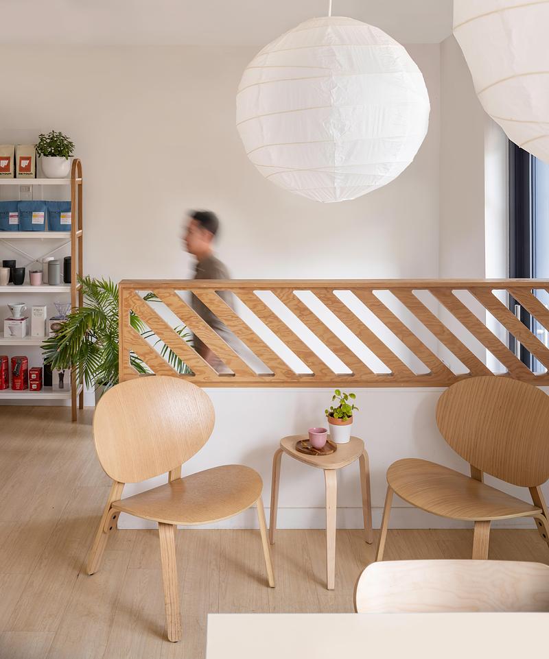 Press kit | 1513-09 - Press release | Lion Coffee - Dubbeldam Architecture + Design - Commercial Interior Design - Framed by a geometric wood partition that maintains the space’s open, airy feel, this cozy corner offers a spot for relaxation, with wood accents and minimalist decor. - Photo credit: Scott Norsworthy