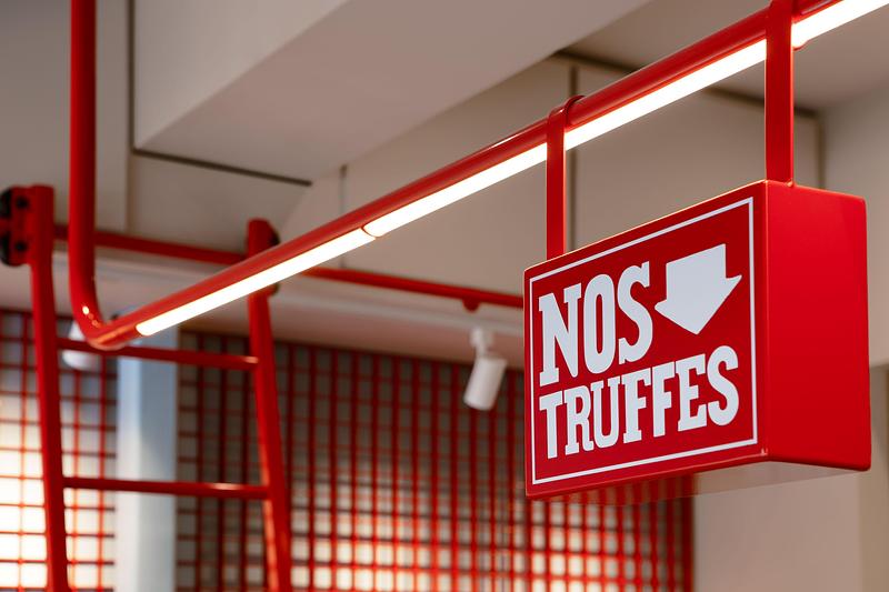 Dossier de presse | 1676-10 - Communiqué de presse | Réinventer la magie du chocolat : une collaboration réussie pour Les Chocolats de Chloé - ADHOC - Design d’intérieur commercial - Structure tubulaire suspendue intégrant l’éclairage architectural et la signalisation, ajoutant une touche audacieuse de couleur - Crédit photo : Vicky Rousseau