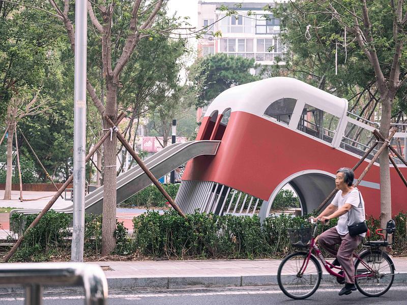 Press kit | 7020-04 - Press release | Old Beijing Bus: The Public Children's Space with a Bus Theme on the Streets of Changping - XISUI Design - Landscape Architecture - Bright background as residents cycling by<br> - Photo credit:  Hu Yihao 
