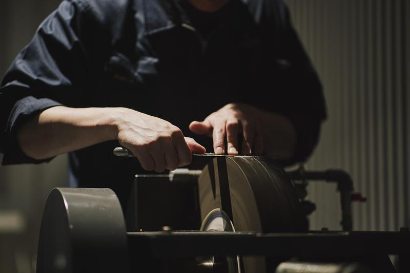 Dossier de presse | 7830-01 - Communiqué de presse | Tojiro Knife Gallery Osaka Wins Dezeen Award 2025 - KATATA YOSHIHITO DESIGN (L/O) - Design d’intérieur commercial - Close-up of knife sharpening in the open maintenance room. - Crédit photo : Masaaki Inoue