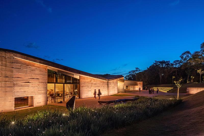 Dossier de presse | 7817-01 - Communiqué de presse | Memorial Brumadinho - Atiaîa Lighting Design - Design d’éclairage - <p class="">External living area, between the entrance Pavilion and the Rift. The openings allow views to the Cafeteria and part of the Meditation Space. Grazing fixtures uplight concrete walls and eaves. The druse's reflecting pool is not illuminated but reflects its surroundings.</p> - Crédit photo : Pedro Mascaro