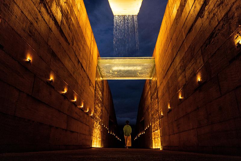 Dossier de presse | 7817-01 - Communiqué de presse | Memorial Brumadinho - Atiaîa Lighting Design - Design d’éclairage - <p class="">From the sculpture's geometric eyes, tears flow continually., forming a veil over the concrete walls. The water, a symbol of memory and purification, runs through the space in two streams until it reaches the reflecting pool under the observation deck, where mourning meets contemplation.</p> - Crédit photo : Leo Drumond/Nitro