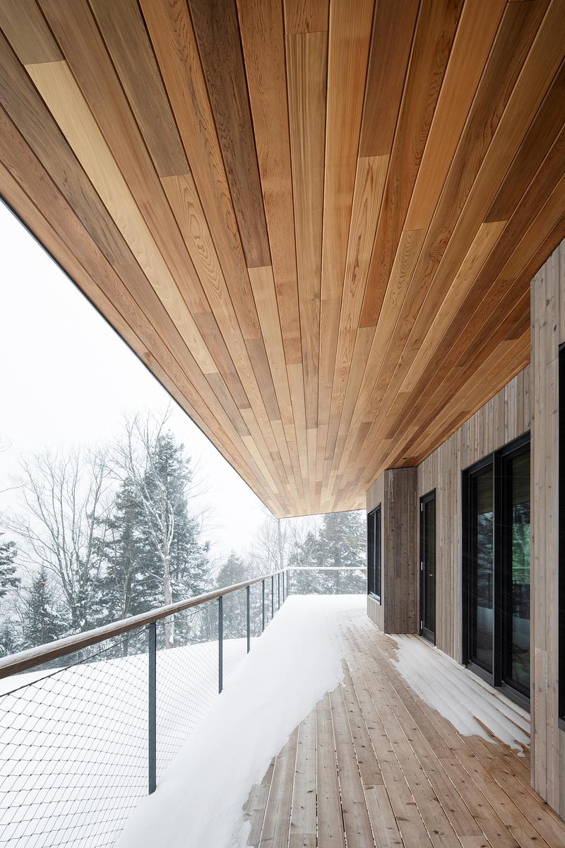 Press kit | 2054-05 - Press release | Laurentian Forest House - RobitailleCurtis - Residential Architecture - Deep overhangs on the south facing deck protect the house during summer and winter months.  The Western Red Cedar ceiling from the interior carries through to the outside. - Photo credit: Adrien Williams