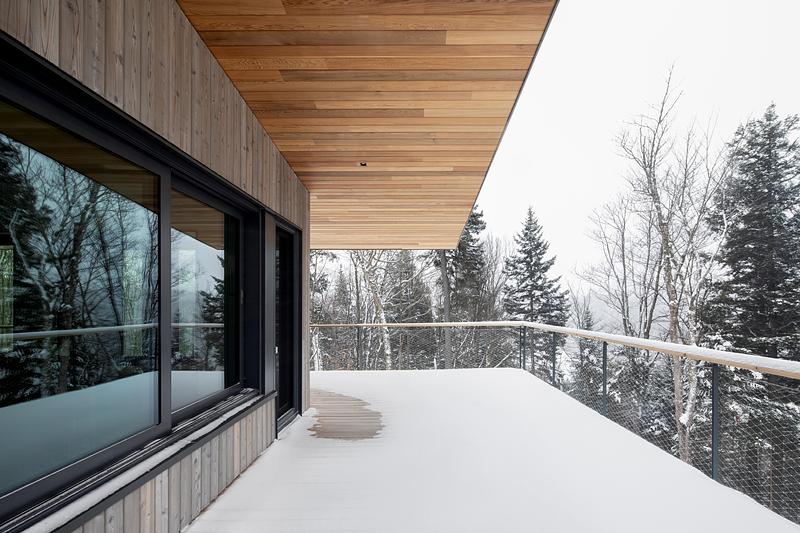 Press kit | 2054-05 - Press release | Laurentian Forest House - RobitailleCurtis - Residential Architecture - Deep overhangs extend over the western portion of the cedar deck as well. The western portion of the deck faces Lac Notre-Dame - Photo credit: Adrien Williams