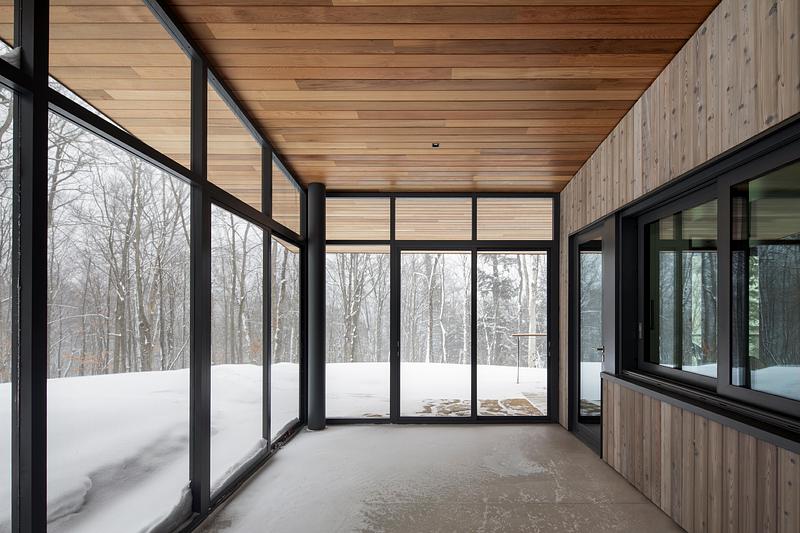 Press kit | 2054-05 - Press release | Laurentian Forest House - RobitailleCurtis - Residential Architecture -  A view of the screened in dining porch  The sliding kitchen window opens the kitchen to the porch in warmer months.  - Photo credit: Adrien Williams