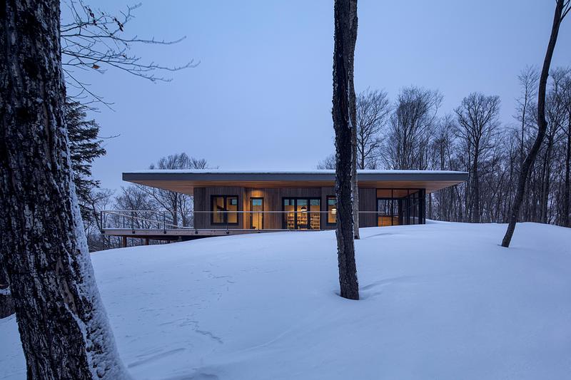 Press kit | 2054-05 - Press release | Laurentian Forest House - RobitailleCurtis - Residential Architecture - A view from the edge of the southern forest looking north to the living bar. - Photo credit: Adrien Williams