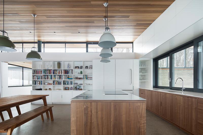 Press kit | 2054-05 - Press release | Laurentian Forest House - RobitailleCurtis - Residential Architecture - A view of the open-plan kitchen and dining areas.  A stainless steel counter and walnut cabinetry are used on the island. - Photo credit: Adrien Williams