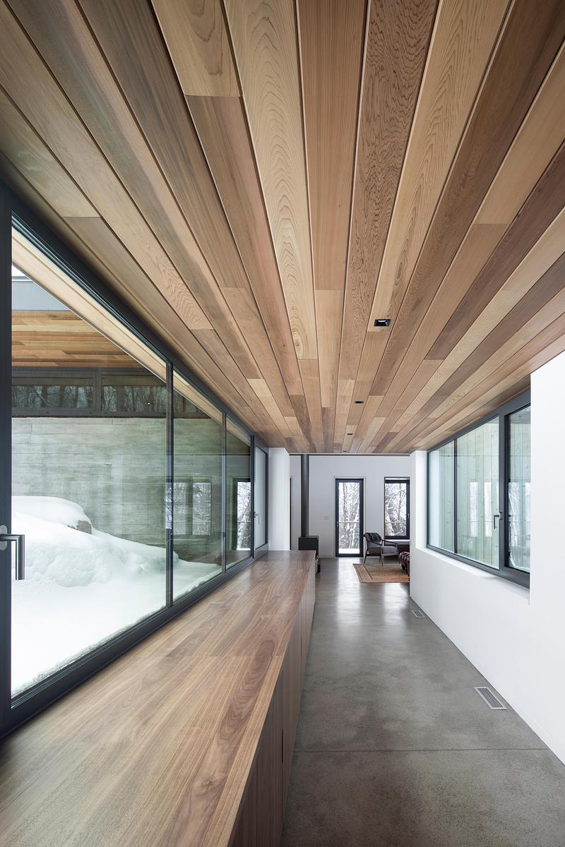 Press kit | 2054-05 - Press release | Laurentian Forest House - RobitailleCurtis - Residential Architecture -  A view from the entry hall down the glass corridor to the living bar.  Radiant heated concrete floors are throughout the house.  - Photo credit: Adrien Williams