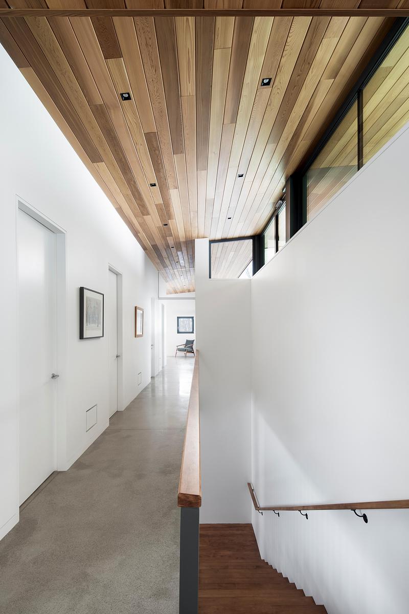 Press kit | 2054-05 - Press release | Laurentian Forest House - RobitailleCurtis - Residential Architecture - A view looking north down the length of the sleeping bar towards the primary bedroom and down the stairs to the lower level. - Photo credit: Adrien Williams