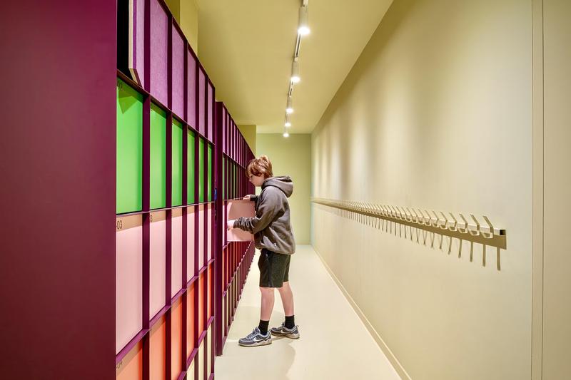 Dossier de presse | 7860-01 - Communiqué de presse | KiMu Children's Art Museum Opens in Amsterdam - KiMu Kinderkunstmuseum - Art - Cloak room with locker system by i29 architects, developed under their new label Elements Amsterdam, combined with a row of old school coat hooks at children’s height.  - Crédit photo : Aiste Rakauskaite