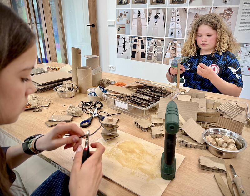 Dossier de presse | 7860-01 - Communiqué de presse | KiMu Children's Art Museum Opens in Amsterdam - KiMu Kinderkunstmuseum - Art -   Uma (15) and Doris (13) at work in the 3D atelier, a ‘prepared environment’ with richly set tables or floor arrangements with materials and tools that invite independent work.    - Crédit photo : Morad Bouchakour