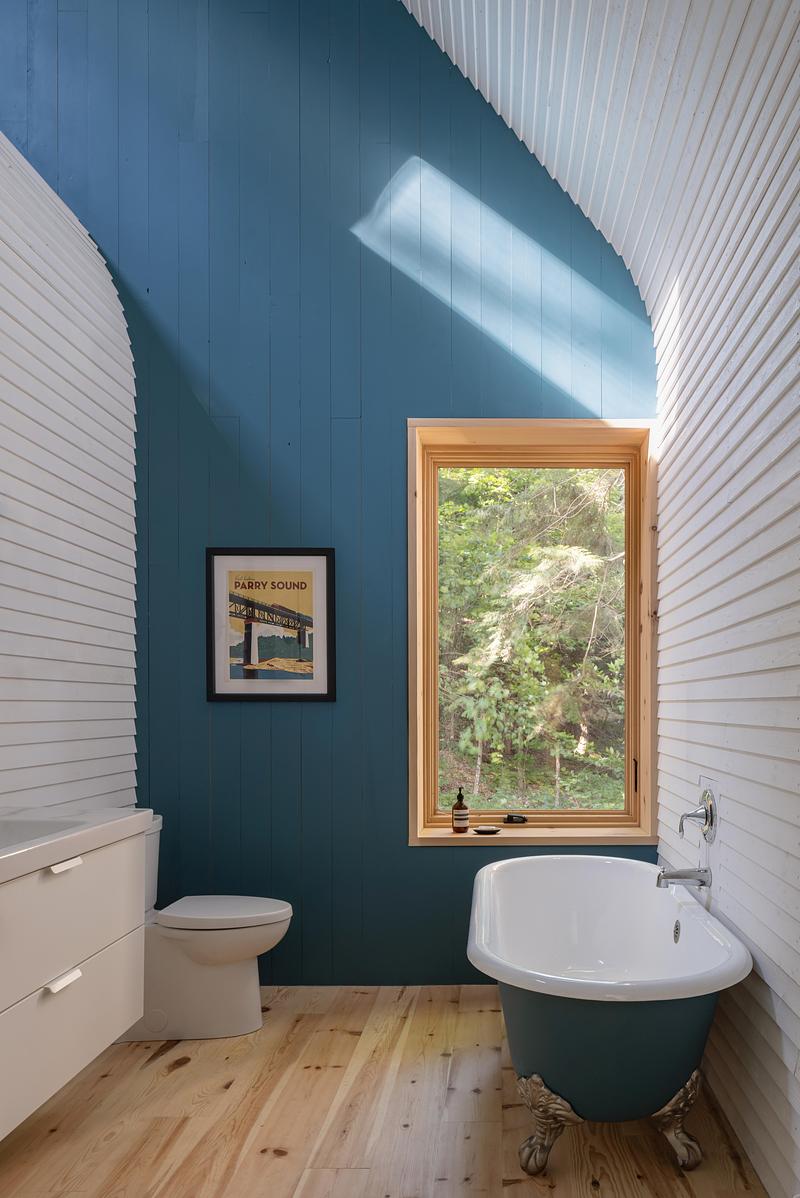 Press kit | 2682-03 - Press release | DogTrot Magnetawan - Williamson Williamson inc - Residential Architecture - The bathroom has a reclaimed bathtub painted to match the south gable wall.  - Photo credit: Scott Norsworthy