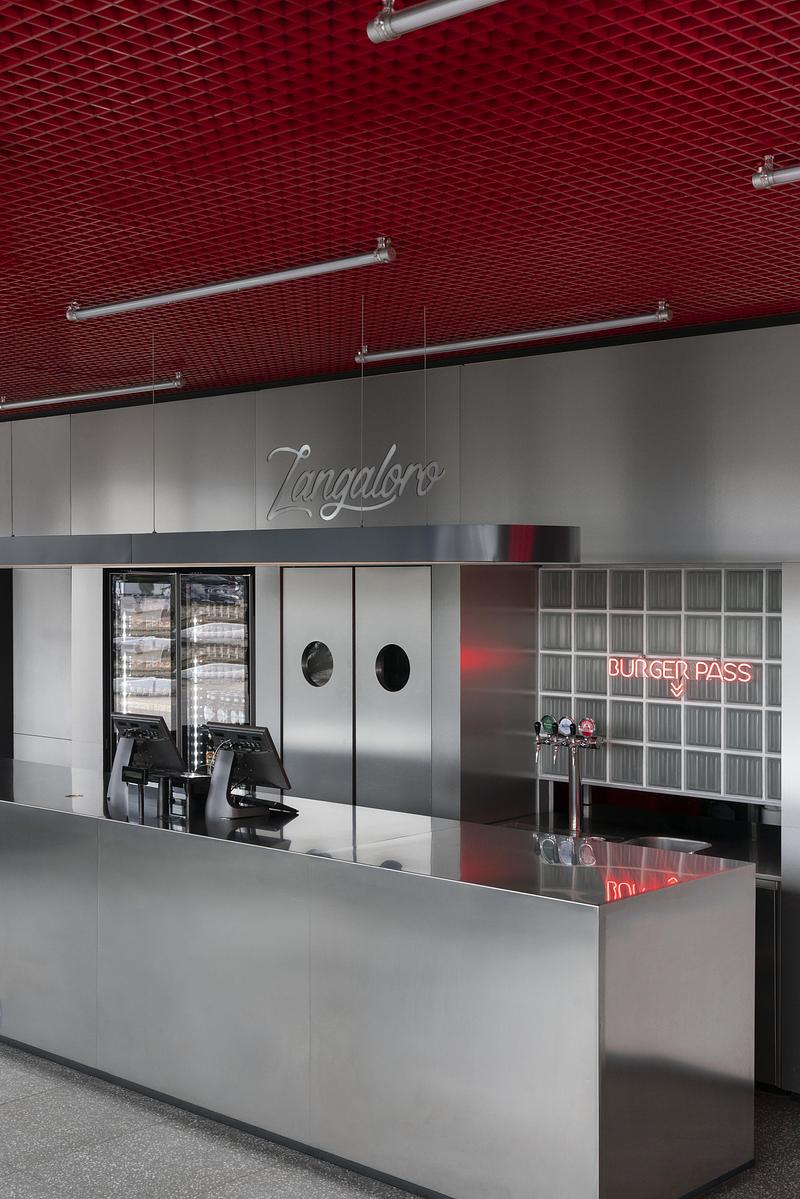Dossier de presse | 4232-24 - Communiqué de presse | Un diner contemporain comme système spatial - Didea - Architecture commerciale -  Le passe-plat, encadré de pavés de verre et d'une enseigne lumineuse rouge, transforme un seuil fonctionnel en véritable point focal de l'architecture  - Crédit photo : Paolo Riolzi