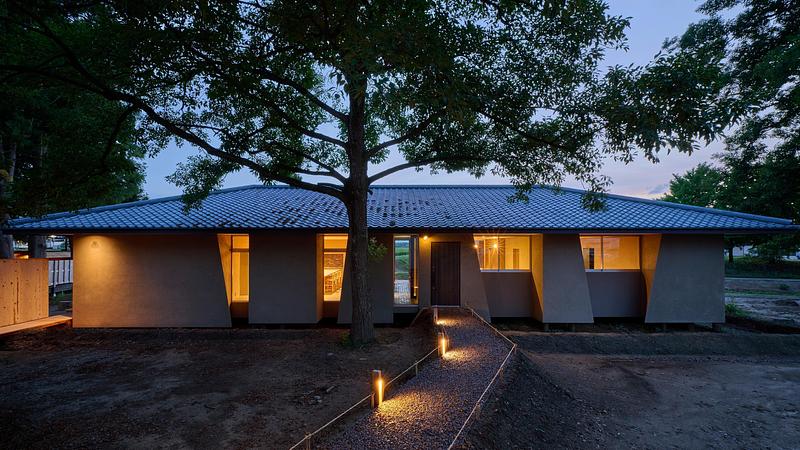 Press kit | 7919-01 - Press release | Né Wins Architecture + Environment by Public Vote at the Architizer A+Awards 2026 - Ahead of the Curve Inc. - Commercial Architecture - The auberge at dusk beneath a large tree, its windows lit from within. - Photo credit: Hiroki Kawata