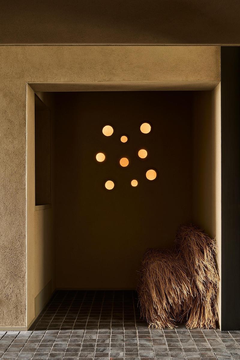 Press kit | 7919-01 - Press release | Né Wins Architecture + Environment by Public Vote at the Architizer A+Awards 2026 - Ahead of the Curve Inc. - Commercial Architecture - An earthen alcove lit by a cluster of small pendant lamps. - Photo credit: Hiroki Kawata