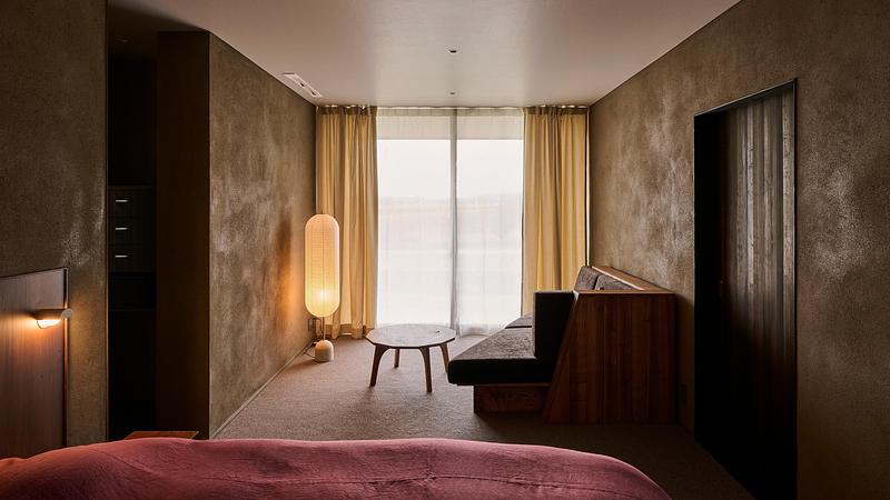 Press kit | 7919-01 - Press release | Né Wins Architecture + Environment by Public Vote at the Architizer A+Awards 2026 - Ahead of the Curve Inc. - Commercial Architecture - A guest room with earthen walls and a window onto the grounds; the auberge receives a single group per day. - Photo credit: Hiroki Kawata