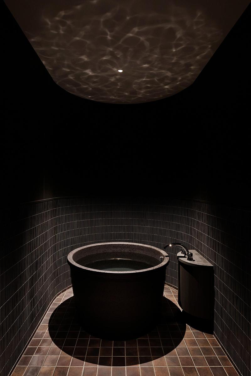 Press kit | 7919-01 - Press release | Né Wins Architecture + Environment by Public Vote at the Architizer A+Awards 2026 - Ahead of the Curve Inc. - Commercial Architecture - The bath, a round tub set in a darkened, textured room. - Photo credit: Hiroki Kawata