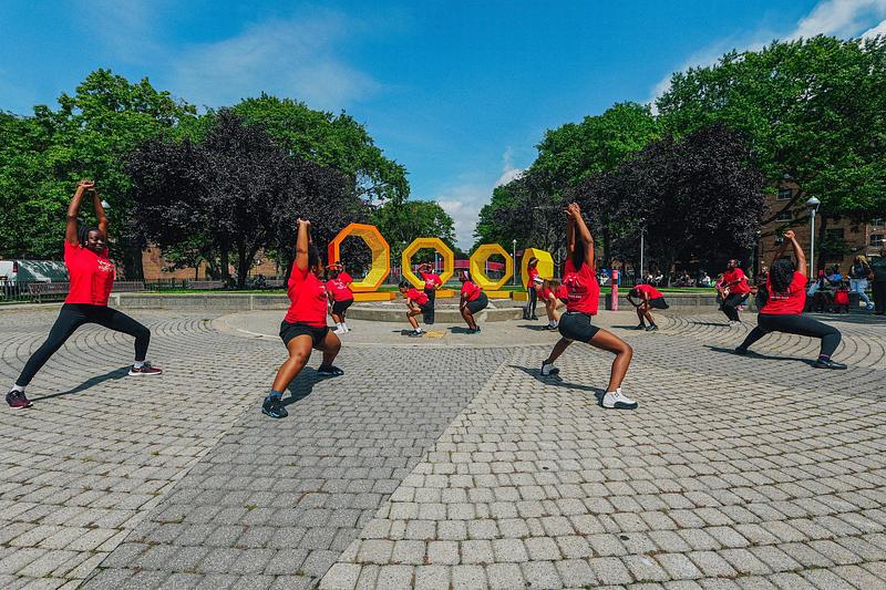 Press kit | 5595-13 - Press release | The Urban Conga Unveils “Revolving Voices” at New York Public Housing in Collaboration with Local Poet Tamra Cosby - The Urban Conga - Art - Local Astoria dance team performs in front of the artwork.  - Photo credit: Tameek Williams