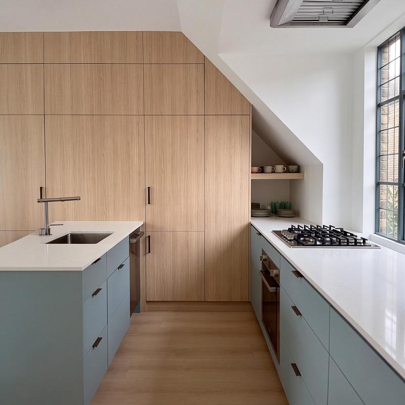 Dossier de presse | 2344-04 - Communiqué de presse | Three Homes on One Toronto Lot Create Room to Stay - baukultur/ca - Architecture résidentielle - Laneway home kitchen with white oak cabinetry, muted blue fronts and an island beneath the sloping ceiling. - Crédit photo : baukultur/ca