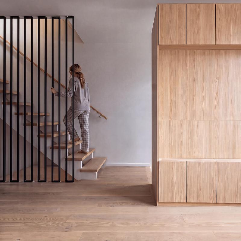 Dossier de presse | 2344-04 - Communiqué de presse | Three Homes on One Toronto Lot Create Room to Stay - baukultur/ca - Architecture résidentielle - Unit B staircase combines open timber treads with a black balustrade beside full-height cabinetry zoning the main floor.  - Crédit photo : Jack Gifford Photography