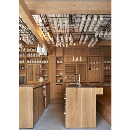 Press kit | 902-02 - Press release | A’ Design Awards 2014 Winners Announced - A' Design Award and Competition - Competition - Gamsei <br>Cocktail Bar by Buero Wagner / F. Wagner with A. Kreft<br><br>PROJECT DESCRIPTION:<br>Gamsei - a cocktailbar rethought When owner and head bartender Matthew Bax opened Gamsei 2013 in Munich's trendy neighbourhood Glockenbach, he introduced hyper-localism to a field of practice which had till then been mainly confined to the food scene. At Gamsei, ingredients for cocktails like Lavender Drunk Bee and Frühlingserwachen, are either wildly foraged by Bax and his team or grown by local artesian farmers, thus reestablishing a connection with local products, region and culture and offering something that is unique in its kind. Bax, an Australian artist and founder of three bars, envisioned his fourth as an antidote to the globalization of cocktail bars; why drink the very same cocktail in every bar you go to in the world? Why not experience the excitement of the new when sipping a cocktail? The bar interior, designed by Fabian A. Wagner of Buero Wagner and Andreas Kreft, is a clear continuation of this philosophy – looking for new configurations whilst paying a tribute to the local Bavarian culture and craftsmanship. The ambience of a Bavarian beer hall has been applied to the 40m² interior through amphitheater-style benches against opposing walls thus eliminating the common separation of bartender and guest. Here interaction is key and everybody has a first row seat. From either tribune guests enjoy a view onto the two centrally placed bars and follow how Bax and his team mix, shake and stir up the cocktails. Also the bars have been stripped of all boundaries: workspace and bar are one. Dried flowers, herbs and leaves are stored and displayed in a wooden built-in cupboard that stretches the full length of the back wall; Besides ingredients, also the coffee machine and even the doors to the bathrooms and laboratory are seamlessly integrated and can be flexibly displayed or disguised behind lattices. Tribunes, bars and cupboards are made of solid oak with a natural oil finish. White ceramic bottles, containing self-made liqueurs, syrups and essences, are suspended from a black steel mesh attached to the ceiling. In-between light bulbs make for a reduced lighting scheme by night. Just like Bax’s cocktail ingredients, the architects procured all materials such as wood, steel and ceramics (custom-made by Gefäß &amp; Objekt, Bachern) locally, and worked in close collaboration with local carpenters and manufacturers to produce custom-made solutions. Gamsei is a wholly integrated concept that turns the event of drinking a cocktail into a novel experience. The refreshing take on the cocktail bar extends further: bartenders, dressed in uniform leather aprons, serve their guests an amuse-gueule, such as “Biersand”, after taking their coats upon entering, and the tribunes on either side - allow for sports broadcasts.&nbsp;<br> - Photo credit: Photographer Jann Averwerser, Gamsei, 2013