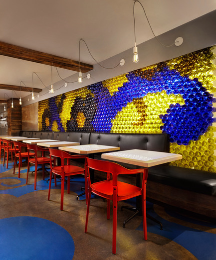 Press kit | 1048-09 - Press release | Spanish-inspired tapas restaurant Barsa Taberna captures the energy of the running of the bulls - +tongtong - Commercial Interior Design - On the other side of the bar, red chairs encase custom-designed tables that feature laminate top with a wooden edge. Above the banquet is a glass wall made of 1,500 coloured wine bottles, all hand-cut by the client's friends.<br> - Photo credit: Lisa Petrole Photography<br>
