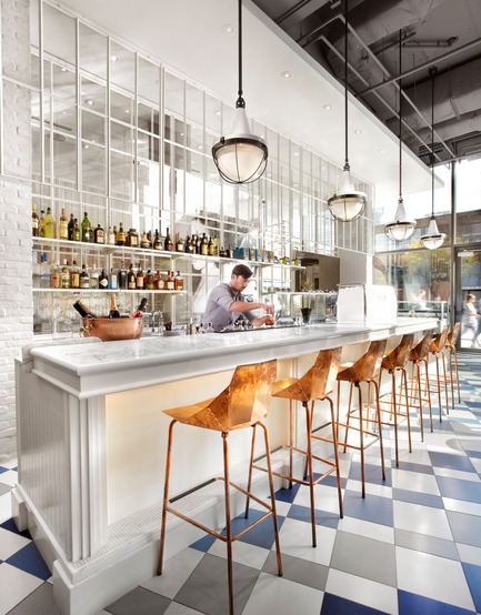 Dossier de presse | 1048-08 - Communiqué de presse | Reinventing the beauty salon experience with Her Majesty’s Pleasure - +tongtong - Design d’intérieur commercial - The one side of the room consists of a seemingly ornate, yet stripped down, whitewashed bar topped with white marble. A line of geometrically folded copper stools reflect the coved lights under the bar. - Crédit photo : Lisa Petrole