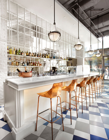 Dossier de presse | 1048-08 - Communiqué de presse | Reinventing the beauty salon experience with Her Majesty’s Pleasure - +tongtong - Design d’intérieur commercial - The one side of the room consists of a seemingly ornate, yet stripped down, whitewashed bar topped with white marble. A line of geometrically folded copper stools reflect the coved lights under the bar. - Crédit photo : Lisa Petrole