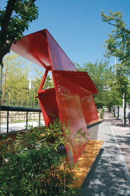 Press kit | 1173-02 - Press release | Winners announce -DFA Awards 2014 - Hong Kong Design Centre (HKDC) - Competition - Project Title: The Red FaceWinning <br>Company: MARUSAI (South Korea)<br><br>“It is something so simple and almost unassuming… it creates a focal point to an area of the city.”Paul Priestman, Design for Asia Awards 2014 Judge&nbsp;<br><br>Synopsis: When designers focus their creativity on the mundane – in this case a bus shelter – the results can often be revolutionary. The Red Face is simultaneously a waiting point, meeting place, playground and viewing platform. All this is achieved in a crisp, sculptural form. The project formed part of an industrial design programme at the Gwangju Design Biennale 2013. The bus stop was originally built as the alighting point for visitors attending the Biennale, so the structure was conceived as a showcase. However it has since become a permanent landmark and its position among some trees also accents the design. Bus stops generically follow the same familiar form: a simple rectangle with simple lines perpendicular and parallel to each other. Challenging those rules entirely, The Red Face is a series of angled, tilted and cantilevered planes and lines that give tension to its overall perspective.