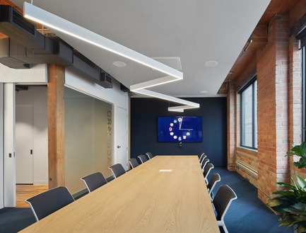 Dossier de presse | 1513-01 - Communiqué de presse | Slack Toronto Office - Dubbeldam Architecture + Design - Design d’intérieur commercial - The elegant oak table by Vitra adds warmth to the executive boardroom. A dropped ceiling over the table conceals technical equipment for various teleconferencing functions, and provides greater acoustic performance. The same angular light fixture threads through the room as an allusion to the continuous lines found throughout the office.&nbsp; - Crédit photo : Shai Gil