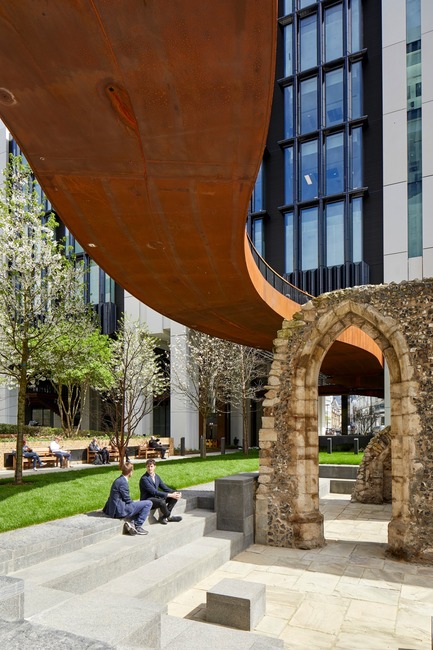 Dossier de presse | 2317-04 - Communiqué de presse | London Wall Place:Building on history - Make Architects - Architecture commerciale -  The remains of St Alphage Church, the new playful pedways overhead and the pale glass reinforced concrete and dark blue, ribbed expanses of faience tiling in the background<br>  - Crédit photo : Make Architects