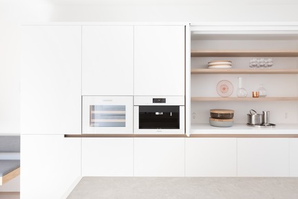 Press kit | 1876-01 - Press release | Unlikely Vancouver Lot Spurs Innovative House Design by Falken Reynolds Interiors - Falken Reynolds Interiors - Residential Interior Design - White lacquer millwork with integrated wine &amp; coffee appliances in white glass to match; open shelving behind doors that tuck away with Corian Solid Surface counter and splash, Bocci 22 outlets and lighting switch - Photo credit: Ema Peter