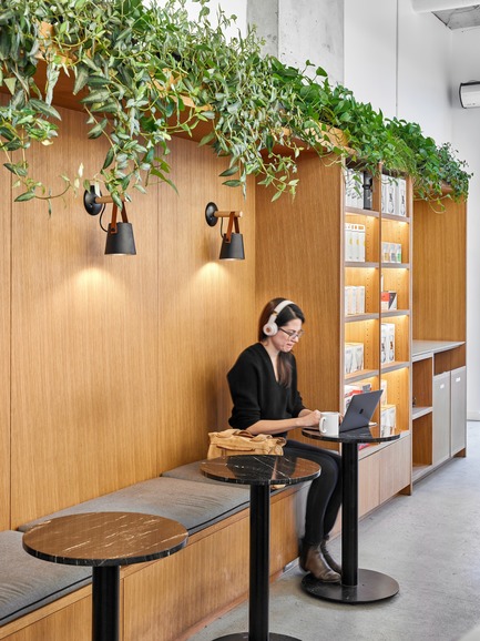 Press kit | 2682-01 - Press release | Innovation Through Design - The Symbiotic Link Between Branding and Architecture - Williamson Williamson Inc. - Commercial Interior Design -   Pilot Ossington Ave. Cafe: A custom bench is carved into the oak cabinetry and topped with greenery.&nbsp;<br>[Completion Date: 2019]<br>   - Photo credit: Scott Norsworthy